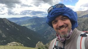 Photo of Xavi smiling in front of a mountainous landscape.